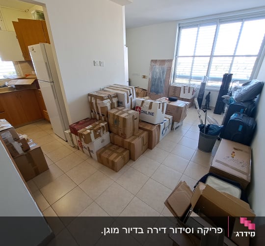 קופסאות קרטון מסודרות בחדר עם מזוודות וציוד ארוז